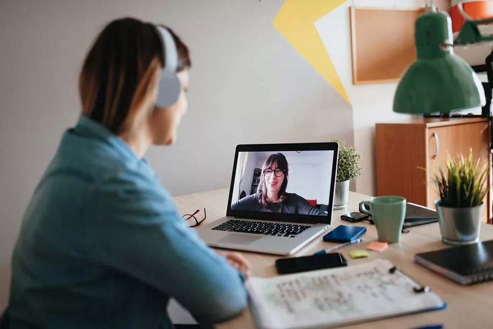 Young woman teleconferencing with sister on laptop on conference call