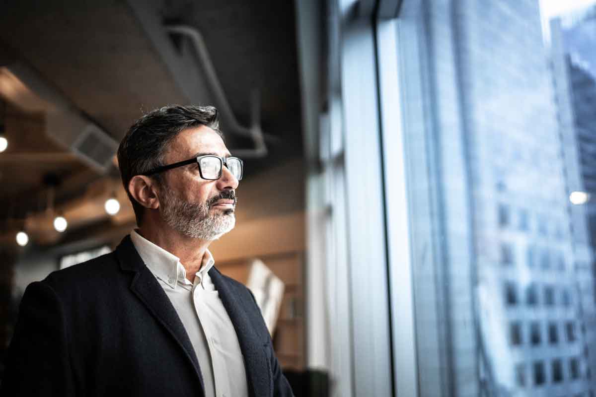 Image of man looking out office building window