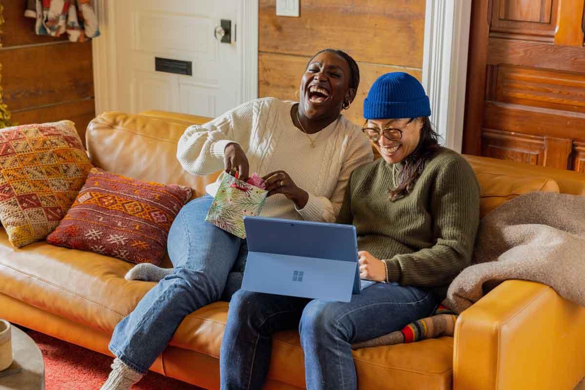 Two people sitting next to each other looking at a computer laughing